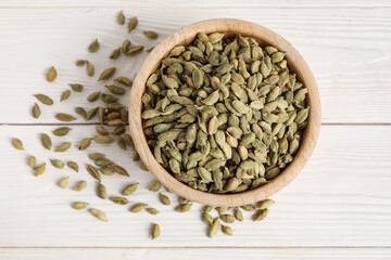 Bowl with cardamom spice on white wooden background