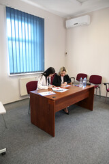 Two women working together in a modern office: signing documents and discussing charts on a flipchart during a work meeting