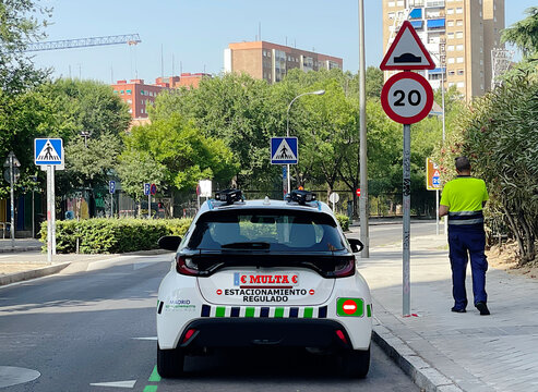 Agente ser de zona poniendo multa en servicio de estacionamiento regulado en la calle con coche y c&aacute;maras de control 