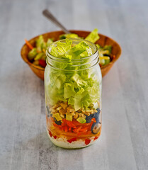 vegetable mason jar salad with lettuce, bell pepper, avocado, olives and blue cheese dressing