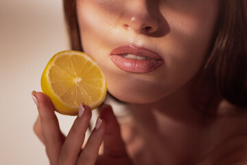 Woman face with lemon slice held near lips in artistic wellness concept. Concept of skincare,...