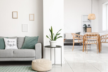 Modern interior of living room with comfortable grey sofa and soft pouf