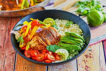 chicken fajita bowl with pan roasted chicken, sauteed red and yellow bell pepper, sliced avocado, fresh lime juice on a bed of cauliflower rice