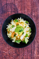 fish taco bowl with shredded cabbage, sliced avocado, fresh cilantro, lime juice and sauteed fish
