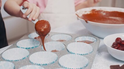 Two sisters are preparing dessert. A four-year-old girl and a teenage girl are making chocolate cupcakes at home in the kitchen. Close up of hands. - Powered by Adobe