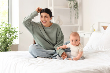 Fototapeta premium Young mother suffering from postnatal depression with her baby in bedroom