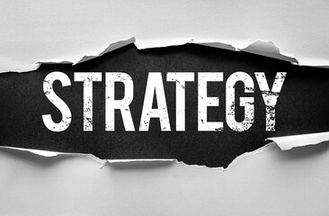 Torn paper reveals the bold, distressed word STRATEGY on a textured background, symbolizing planning, decision-making, and the deliberate actions taken to achieve long-term goals or success