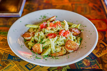 seafood penne pasta with shrimp and scallops tossed in a basil pesto sauce