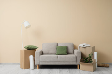 Grey sofa with boxes near beige wall in room on moving day