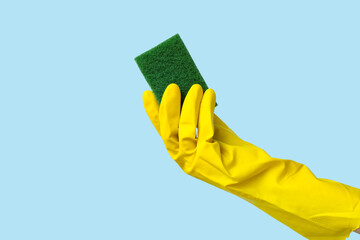 Hand in rubber glove holding sponge for cleaning on blue background