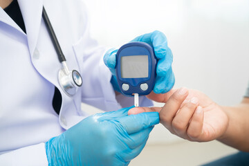 Doctor check diabetes from finger blood sugar level with digital glucose monitor measure and test stripe.