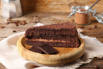 Plate with piece of sweet chocolate cake on wooden background