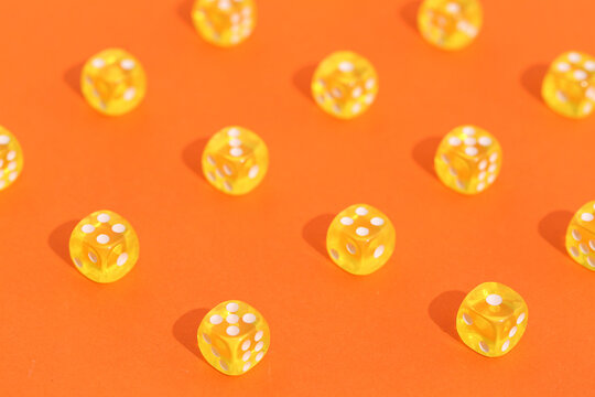 Yellow game dices on orange background, closeup