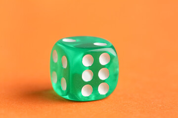 Green game dice on orange background