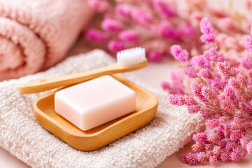 A natural and ecofriendly flat lay of a wooden toothbrush and soap dish on linen with dried flowers