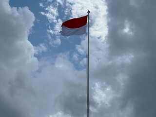 The Indonesian flag flutters proudly in the cloudy sky.