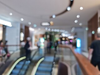 Abstract bokeh image of people on escalator in shopping mall.