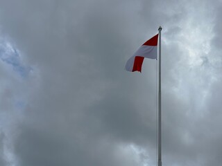 The Indonesian flag flutters proudly in the cloudy sky.