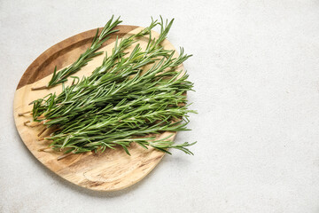 Wooden plate with fresh rosemary twigs on white background