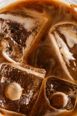 Close-up of Iced Coffee with Swirling Cream and Ice Cubes