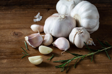 Fresh Garlic Bulbs and Cloves with Rosemary on Rustic Wooden Table