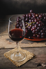 Elegant Glass of Red Wine Surrounded by Fresh Grapes on Wooden Table