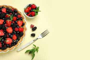 Sweet tart with different fresh berries and mint on yellow background