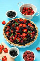 Sweet tart with different fresh berries on blue background