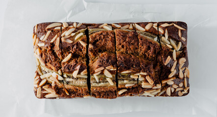 Freshly Baked Banana Bread Loaf with Almonds Sliced on White Surface