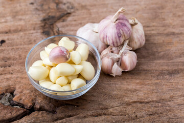 Fresh Garlic Cloves in Glass Bowl on Wooden Surface with Bulbs