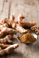 Fresh Turmeric Roots with Ground Turmeric on Wooden Background
