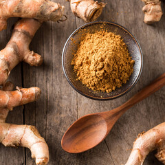 Ground Spices on Wooden Table with Fresh Root and Spoon