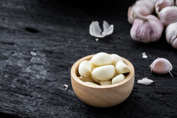Fresh Garlic Cloves in Wooden Bowl on Dark Background for Culinary Use