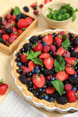 Sweet tart with different fresh berries and mint on wooden background, closeup