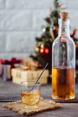 Festive Cocktail Glass with Ice and Bottle Near Christmas Tree