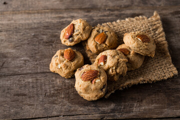 Freshly Baked Cookies with Almonds on Burlap and Wooden Background