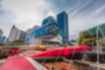 A blurred abstract background of a shopping mall in Shenzhen, China. The background is out of focus, but you can still see a large building with a red sculpture in the foreground.