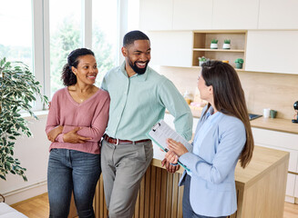 Fototapeta premium Female Real Estate Agent Selling And Showing The Modern Apartment kitchen To His Young Clients, young couple That Are Standing Next To her In The Fancy Apartment