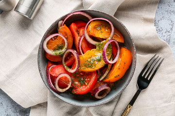 Bowl of fresh tomato salad with red onion on grey background