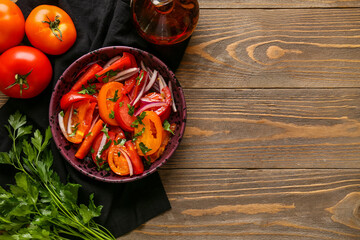 Bowl of fresh tomato salad with red onion and parsley on wooden background