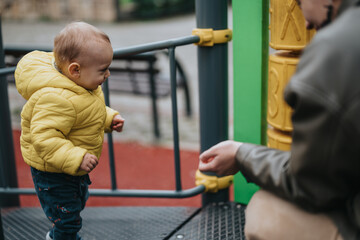 Obraz premium A young child, dressed warmly, plays at a vibrant playground with a supportive adult nearby.