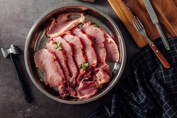 Fresh Raw Meat Slices with Green Herbs on Kitchen Table Surface