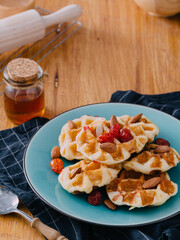 Delicious Waffles Topped with Berries and Nuts on Wooden Table