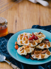 Delicious Waffles with Almonds and Berries on a Blue Plate
