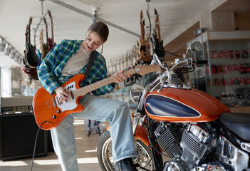 Fototapeta premium A woman plays guitar while sitting on a motorcycle