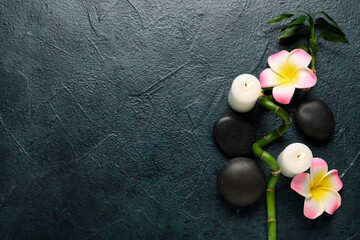 Beautiful spa composition with stones, plumeria flowers and burning candles on dark grunge background