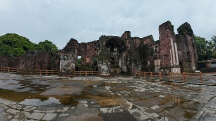  Abandoned Church of St. Augustine ruins in Old Goa, showcasing medieval brick walls under dim...