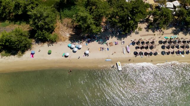Platana beach and sea, sun umbrellas top view, Thassos Island, Greece. Amazing beach with clear blue water. Aerial panoramic drone view from above, top view from drone. Summer holidays Europe
