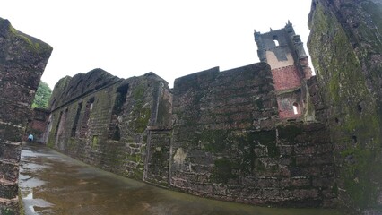  Abandoned Church of St. Augustine ruins in Old Goa, showcasing medieval brick walls under dim...