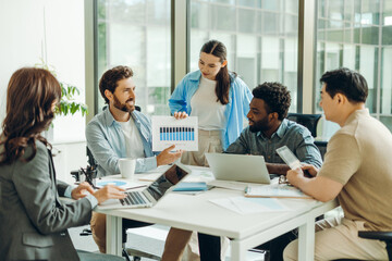 Group of smiling business people working together analyzing financial chart at office meeting